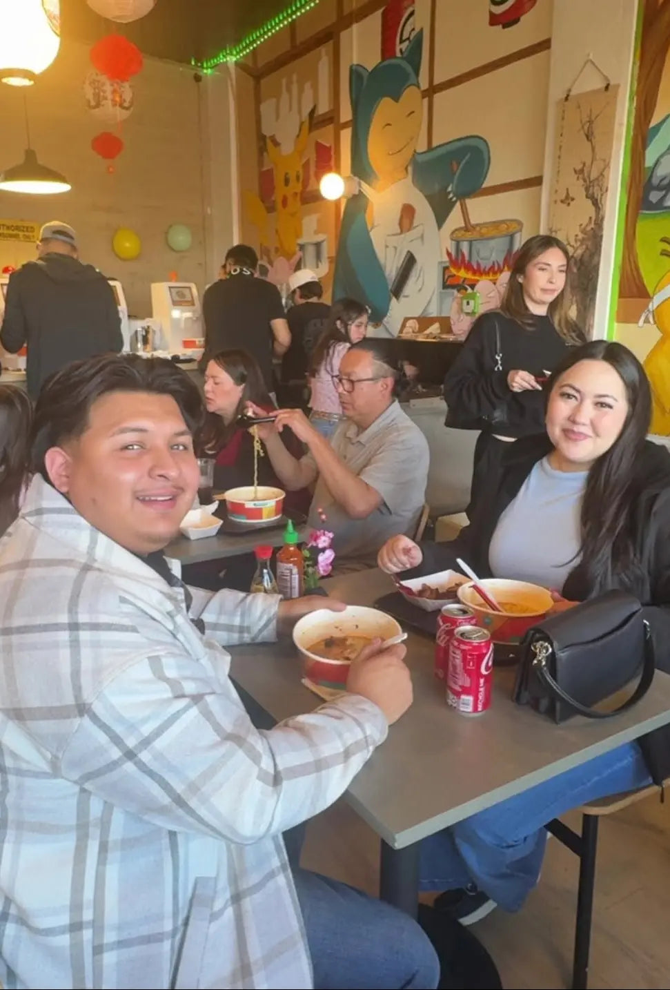 Satisfied customers enjoying hot meals at a vibrant, themed self-serve ramen bar powered by NEO CUCINA automated cookers. This real-world business example demonstrates high customer engagement and a busy dining atmosphere in a smart ramen shop concept.