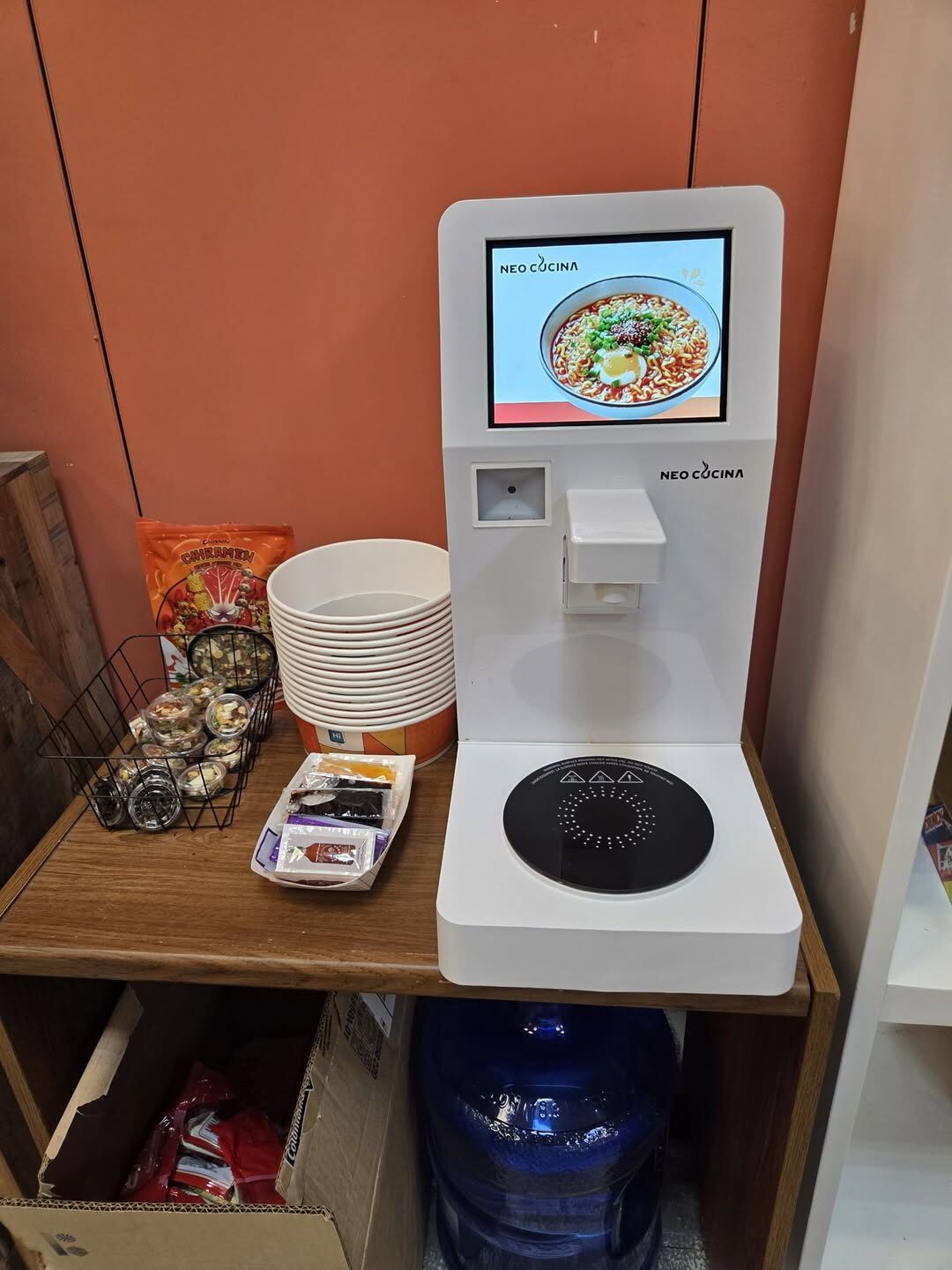 Ramen corner with bowls, seasonings and snacks next to the machine