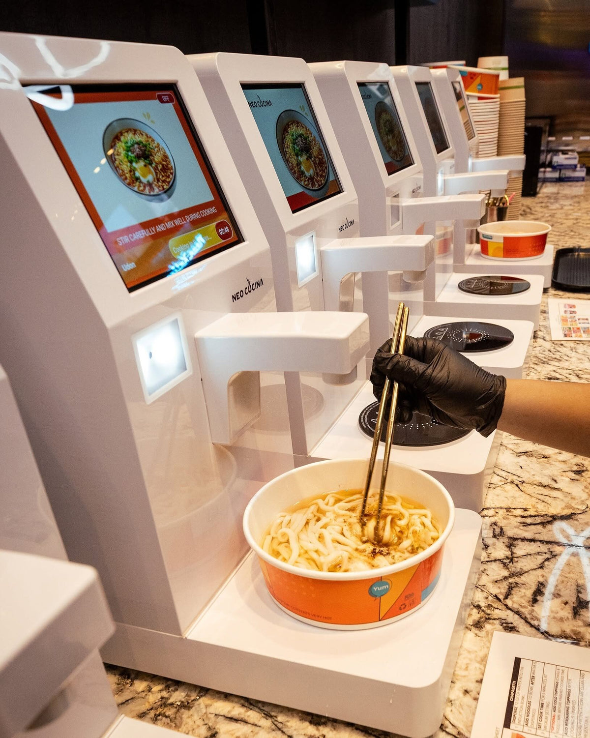 Row of NEO CUCINA Pro machines with a bowl of ramen being stirred at a casino market in Rohnert Park, California