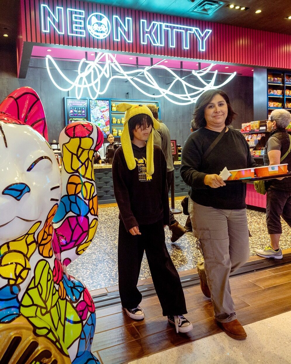 Guests carrying ramen bowls out of an Asian market inside a casino
