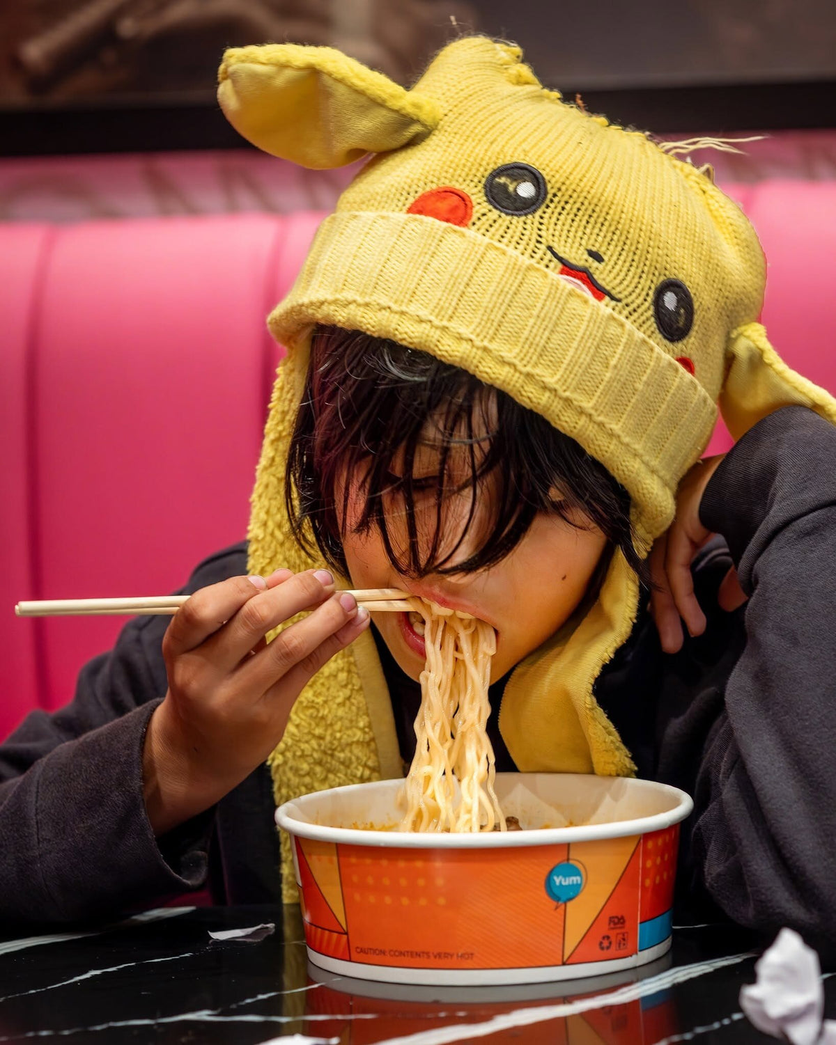 Guest eating a bowl of ramen in a pink booth at a casino market in Rohnert Park, California