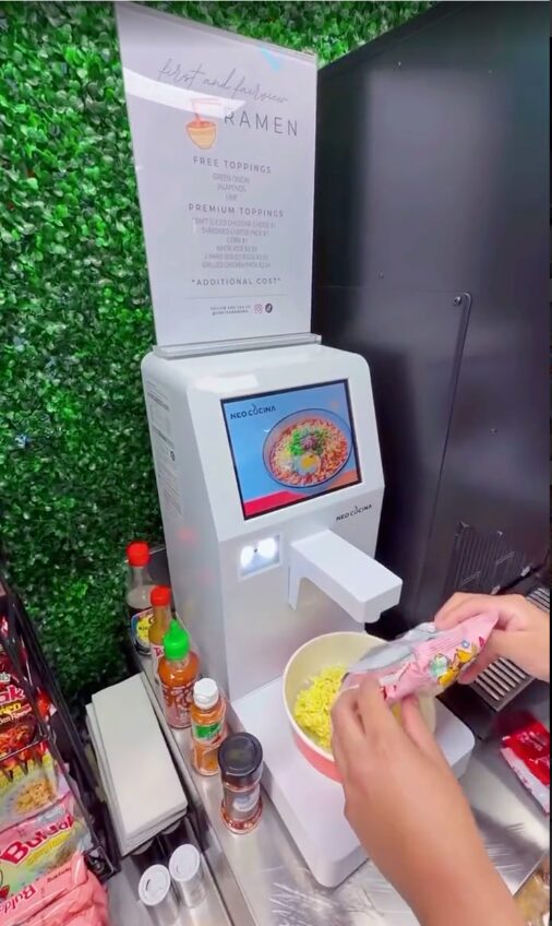 Customer adding sauce to noodles at a NEO CUCINA Pro with a toppings price sign, Santa Ana gas station